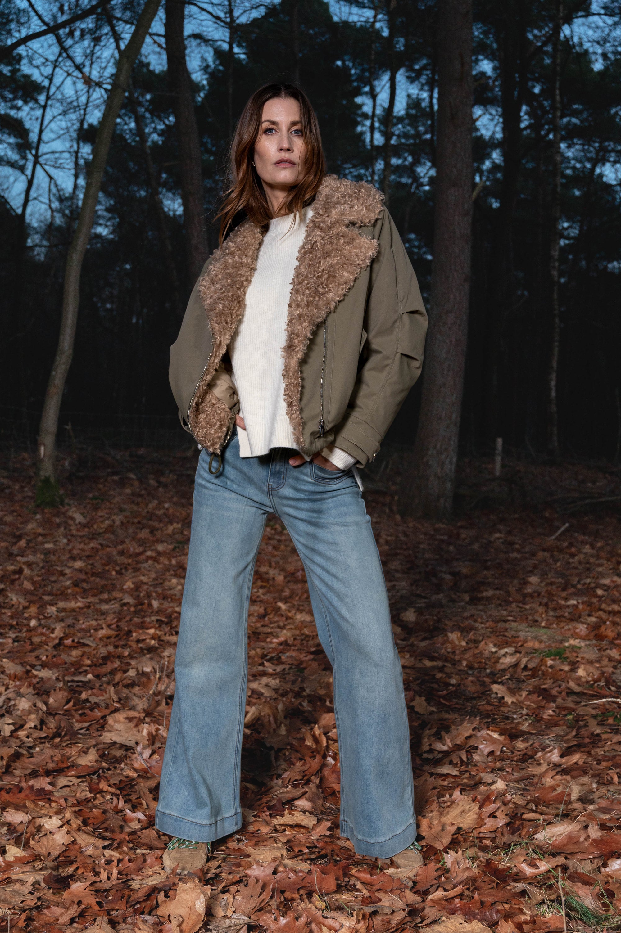 dame draagt stoere najaarslook met legergroene herfstjas met een off-white shirt met lange mouwen op een stoere denim