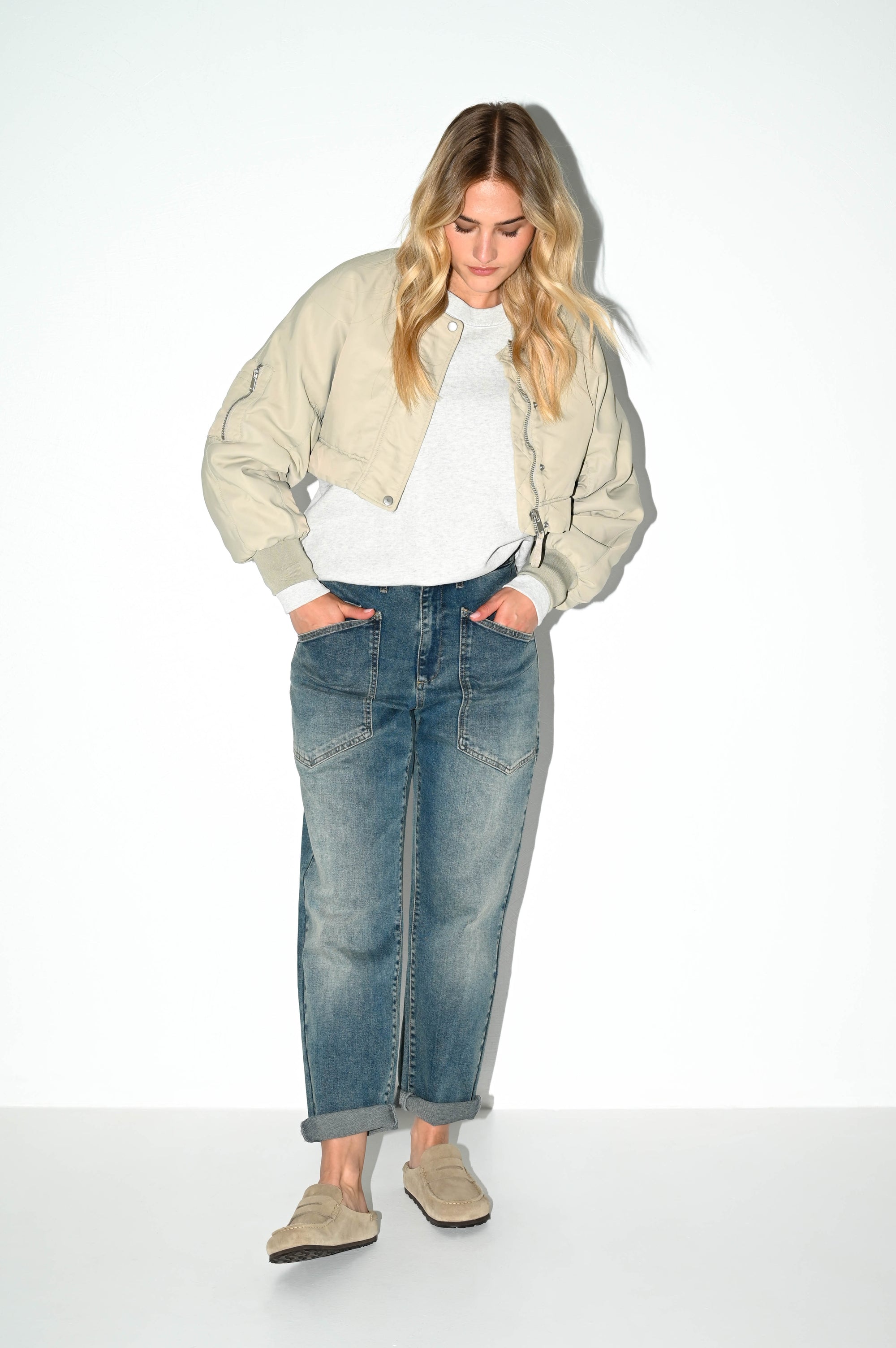 model draagt de jaclin grijsblauwe carrot fit jeans van dnm pure gecombineerd met witte top en off white jasje