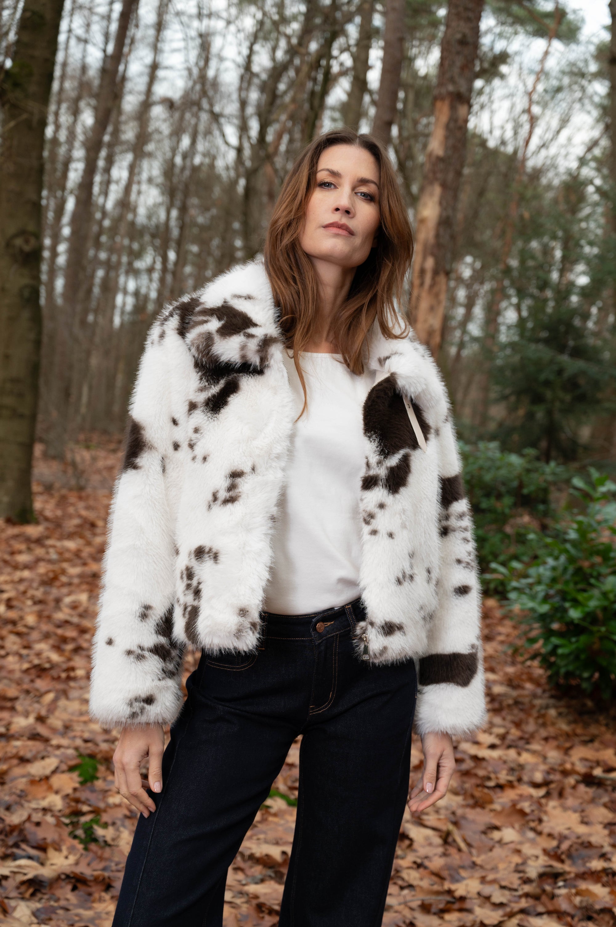 model draagt warm herfstjas met koeienprint op een donkere spijkerbroek 