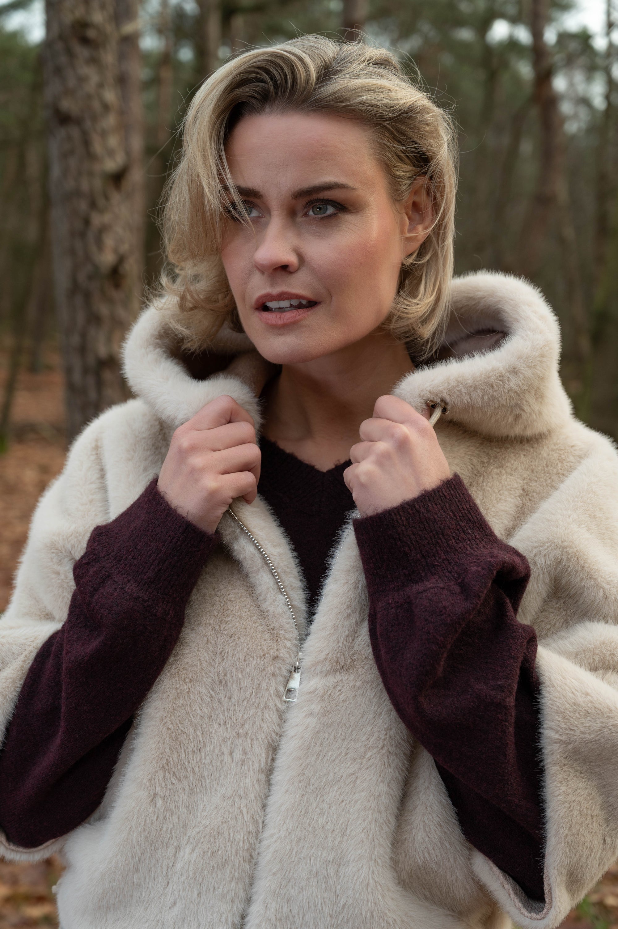 details lichtbeige jasje met capuchon en korte mouwen op een wijnrode trui met lange mouwen gestyled