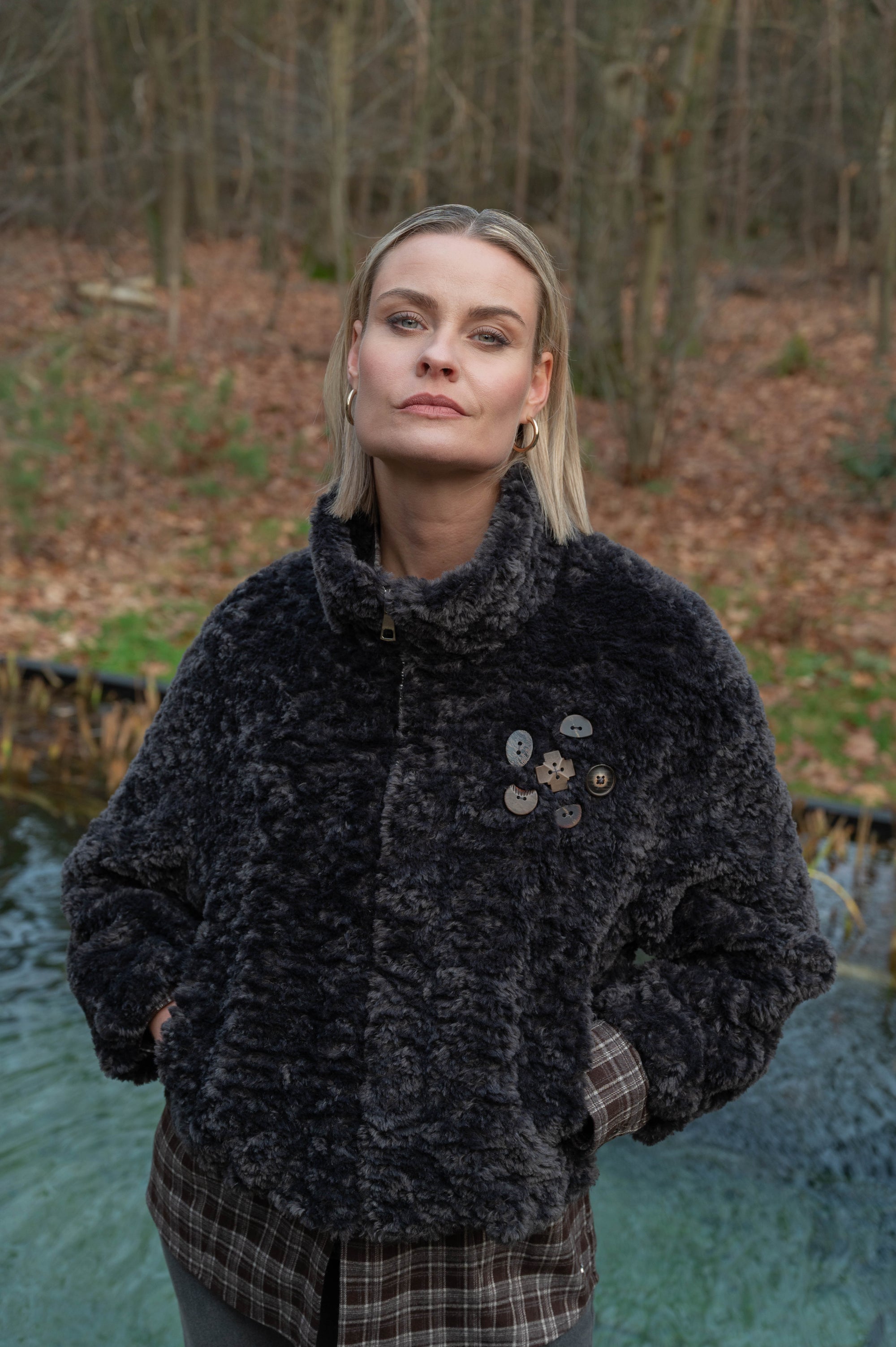 dame draagt een zwartgrijs zacht teddyjasje over een geruite herfstblouse 