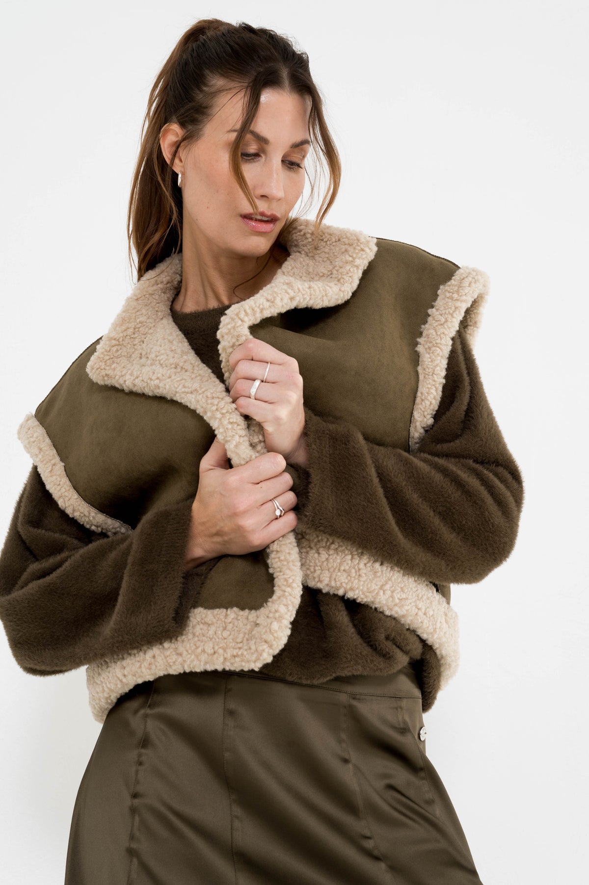 complete mosgroene outfit met gilet in teddystof over een zachte trui en op een satijnlook rok 