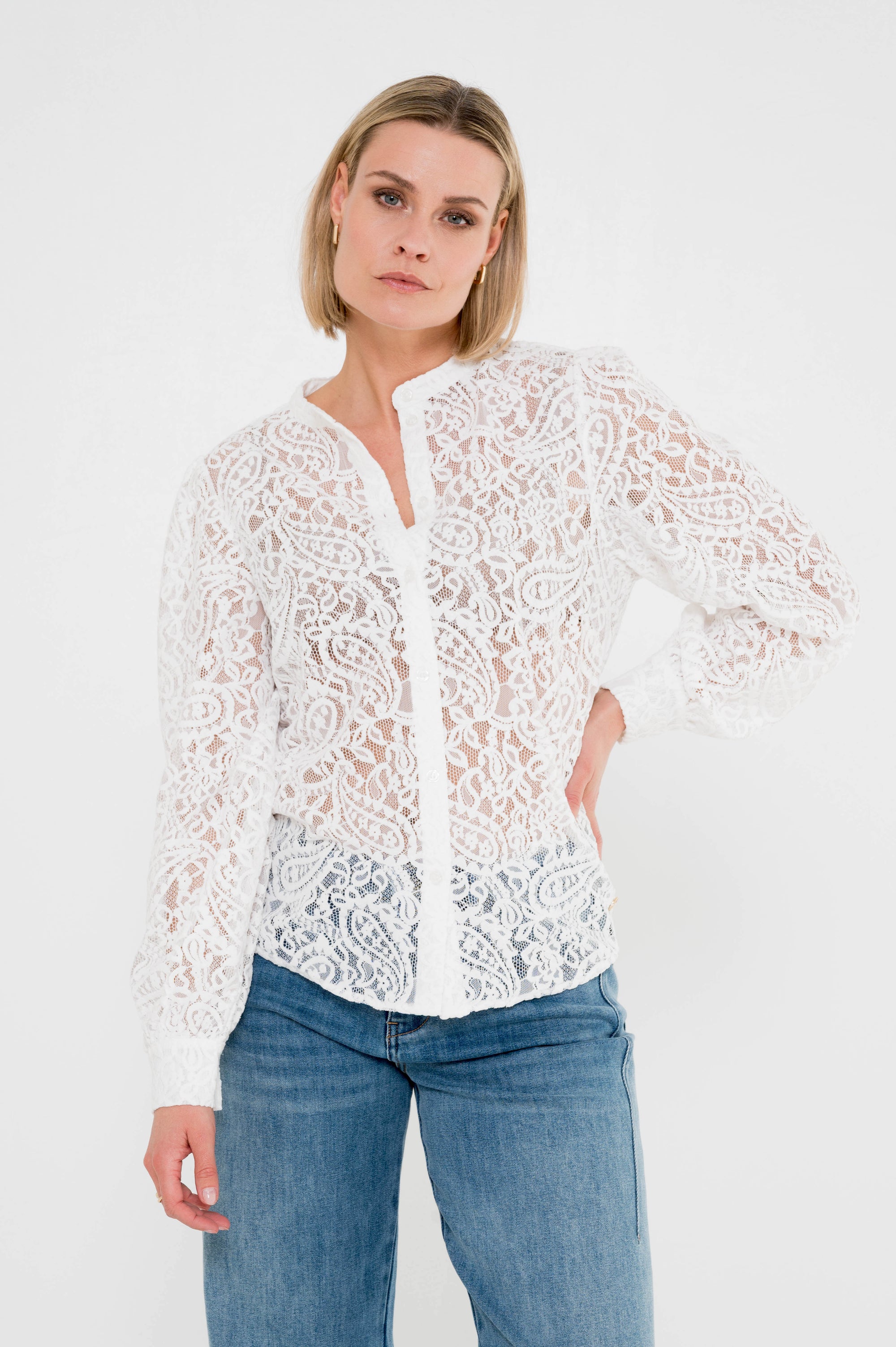 model draagt  offwhite blouse in verfijnd kant met een sierlijk bloemenmotief die licht doorschijnt voor een vrouwelijke touch