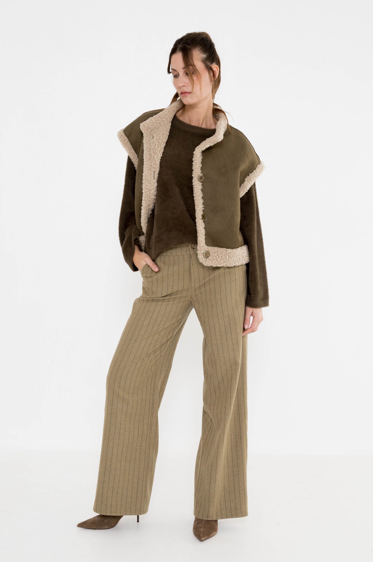 olijfgroen gilet voor dames op een mosgroene trui en met een khaki kleur gestreepte broek