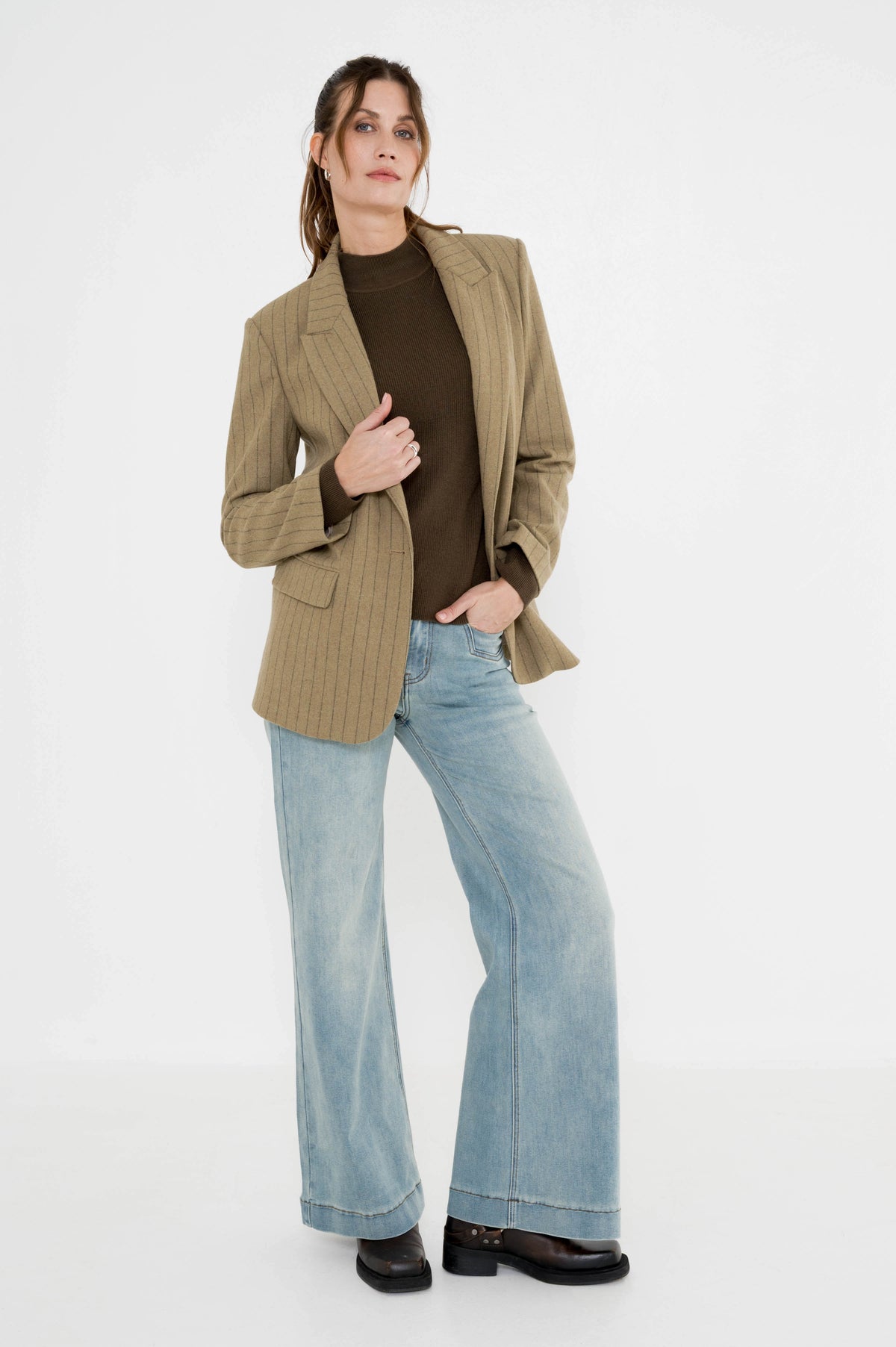 dame draagt de coltrui phenix mosgroen in combinatie met rora blazer khaki gestreept op een lichte spijkerbroek