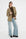 lichte jeans met wijde pijpen en daarboven een khaki blazer met een mosgroene coltrui