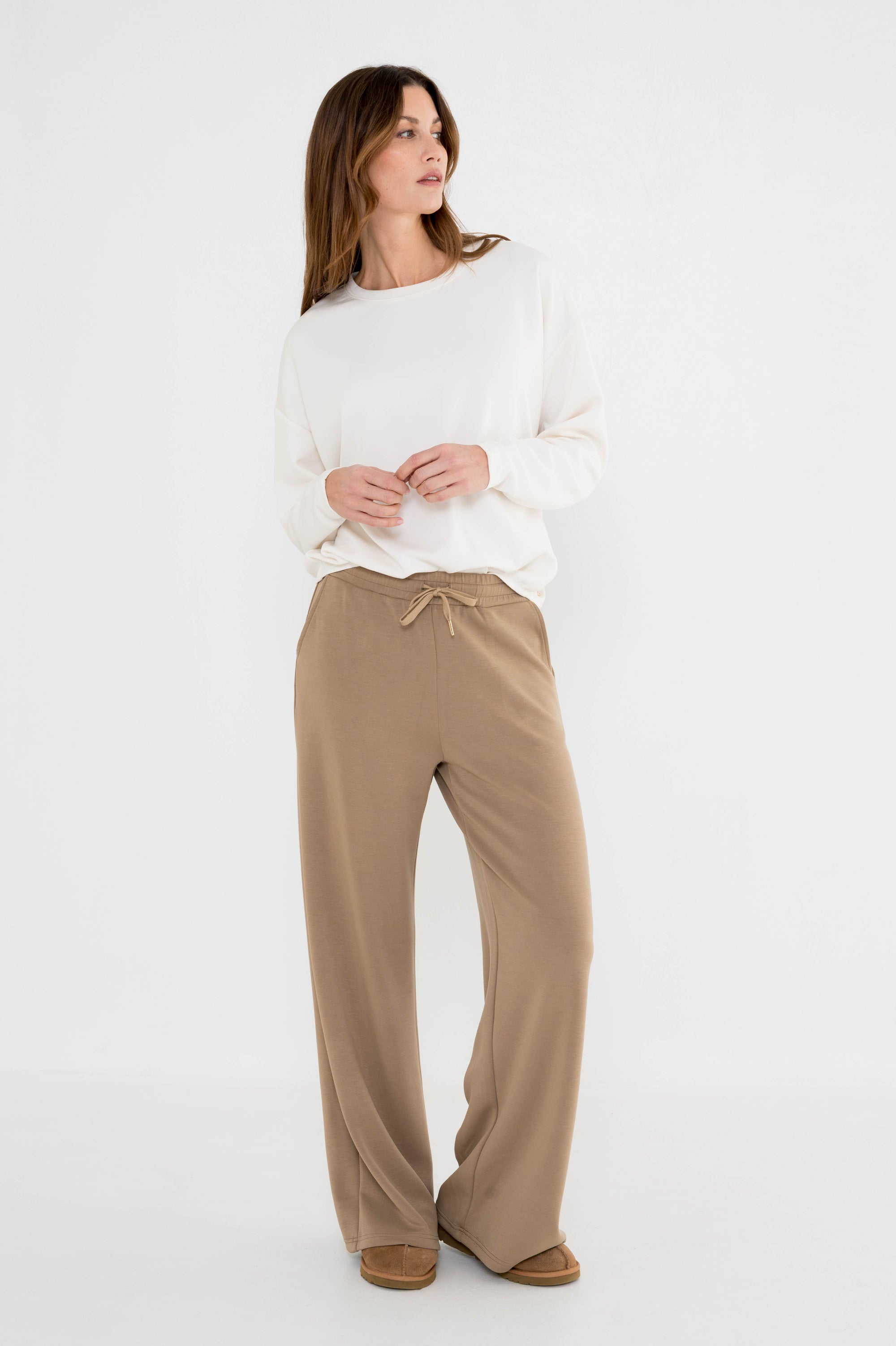 model draagt camel broek vipa met elastische tailleband en strikkoord gecombineerd met een offwhite trui