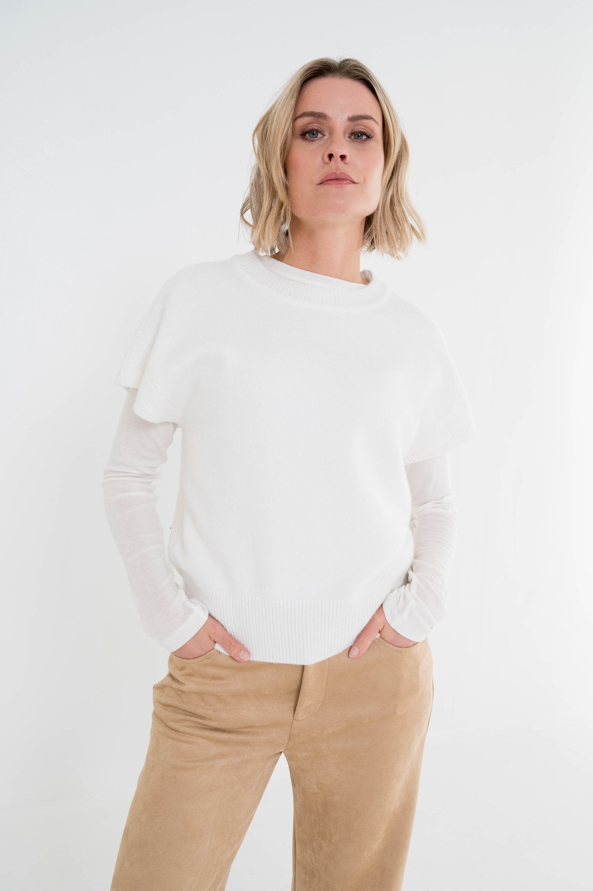 off-white gebreid t-shirt in combinatie met een zandkleurige broek en gedragen over een shirt met lange mouwen in dezelfde kleur als het t-shirt