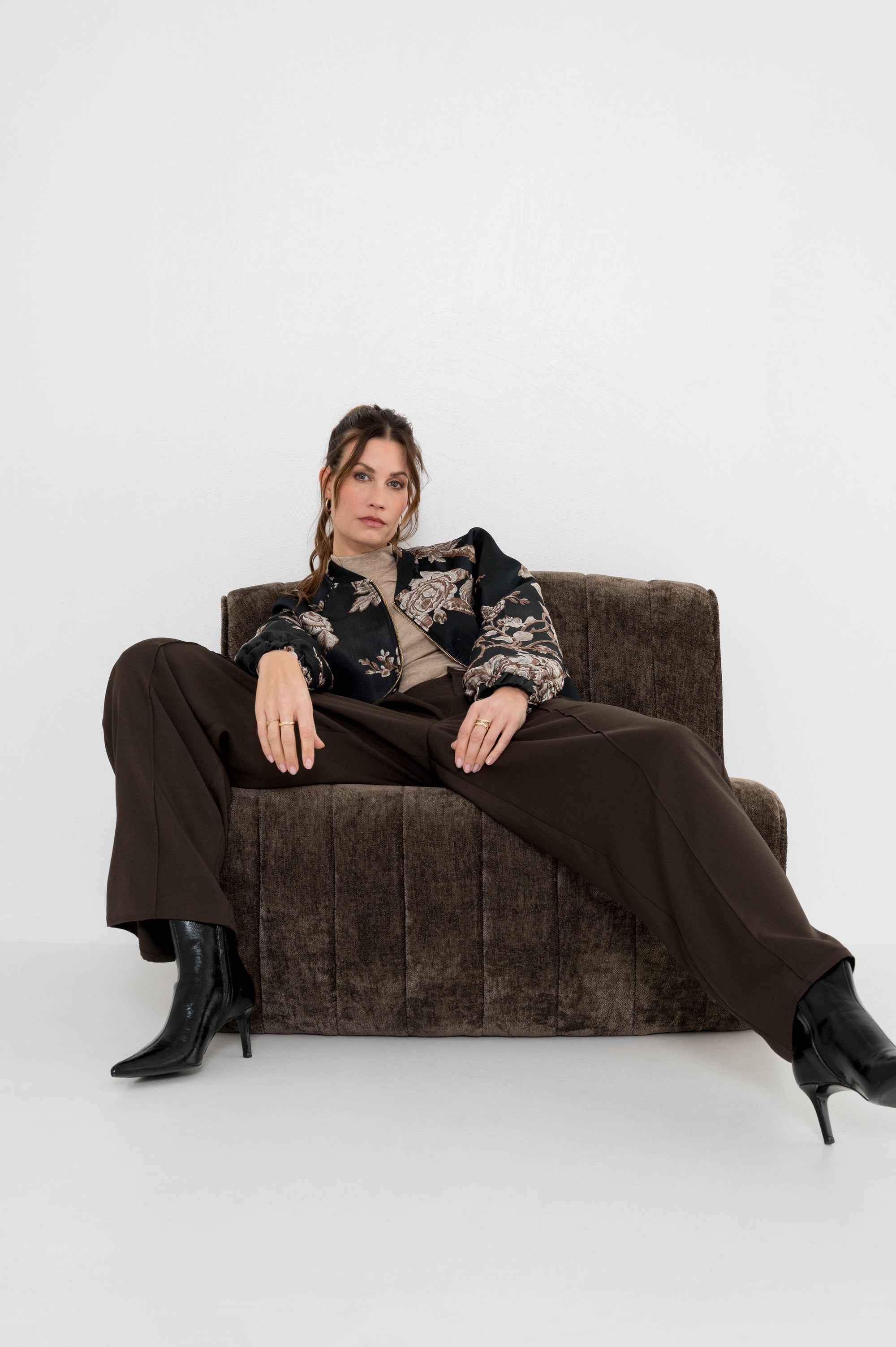 model draagt sevilla pantalon gecombineerd met een beige coltrui en zwart bomberjasje met bloemenmotief die matcht met de hele outfit