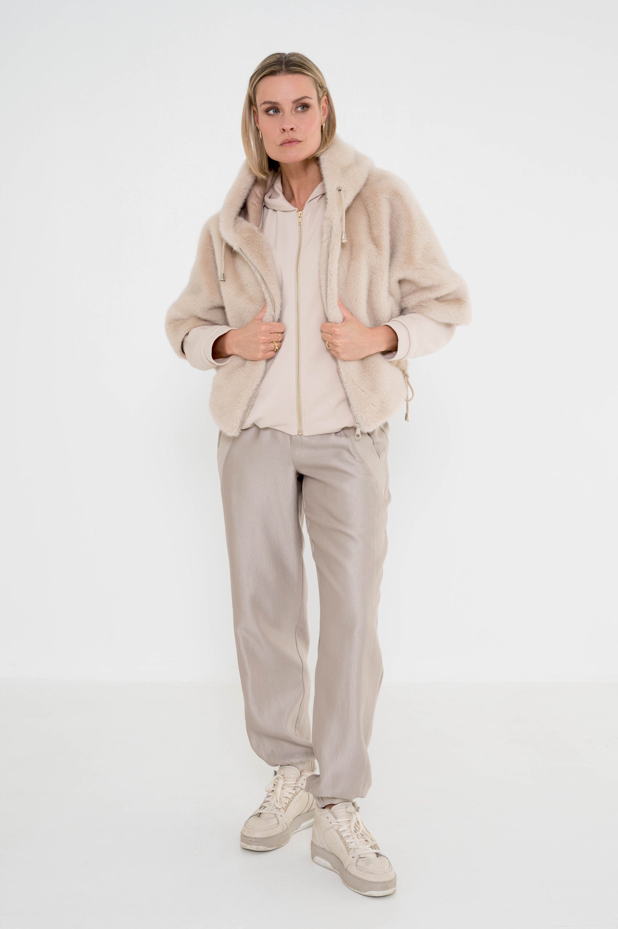 trendy outfit dames met een zandkleur vest, greige broek en over het vest een zacht zandkleur jasje met korte mouwen