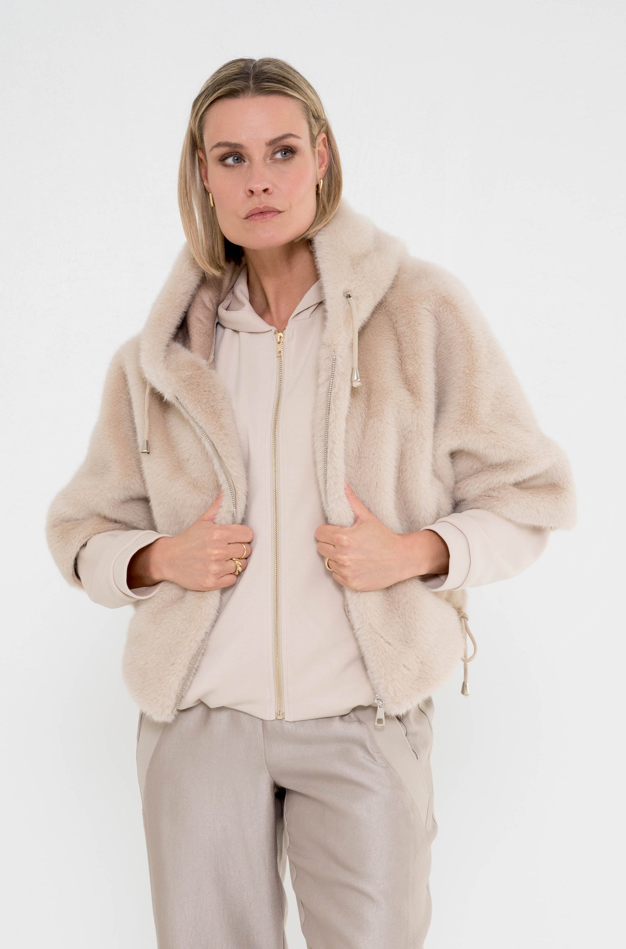 model draagt beige jasje vanina over een zandkleur vest en een greige broek 