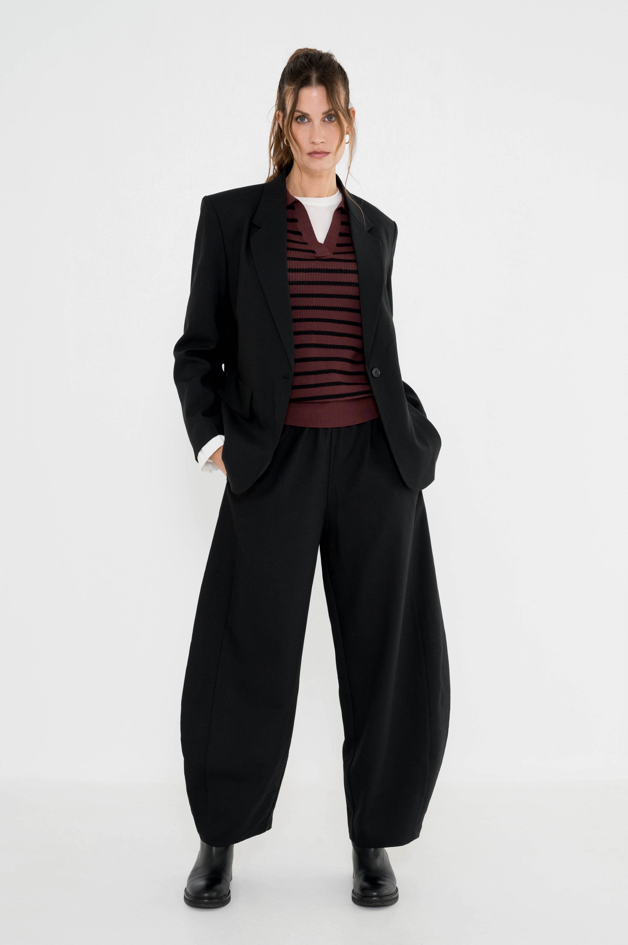 dame heeft de wijde barrel pantalon zwart met een zwarte blazer gecombineerd