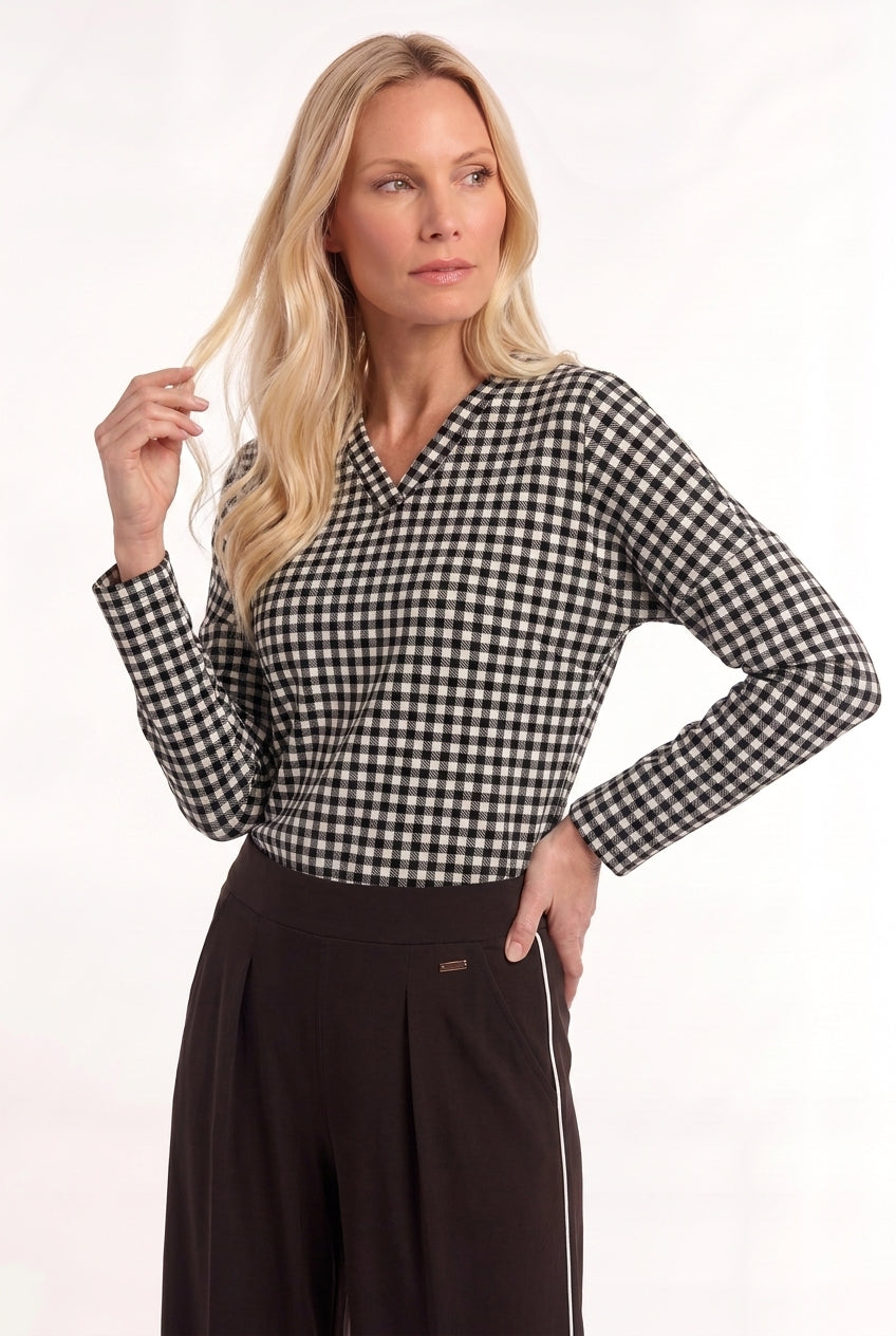 dame draagt een bruin zwart geruite travel top losina met lange mouwen en v-hals op een bruine travel broek