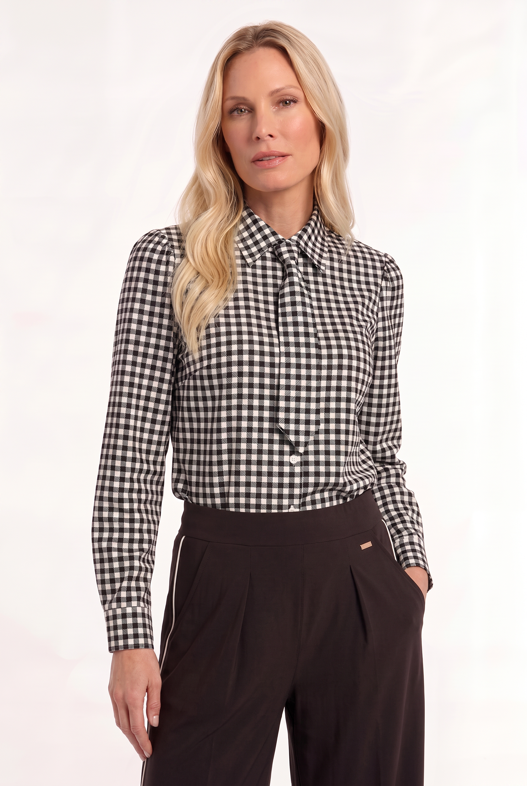 model draagt travelblouse met stropdasdetail met ruitpatroon op een bruine broek