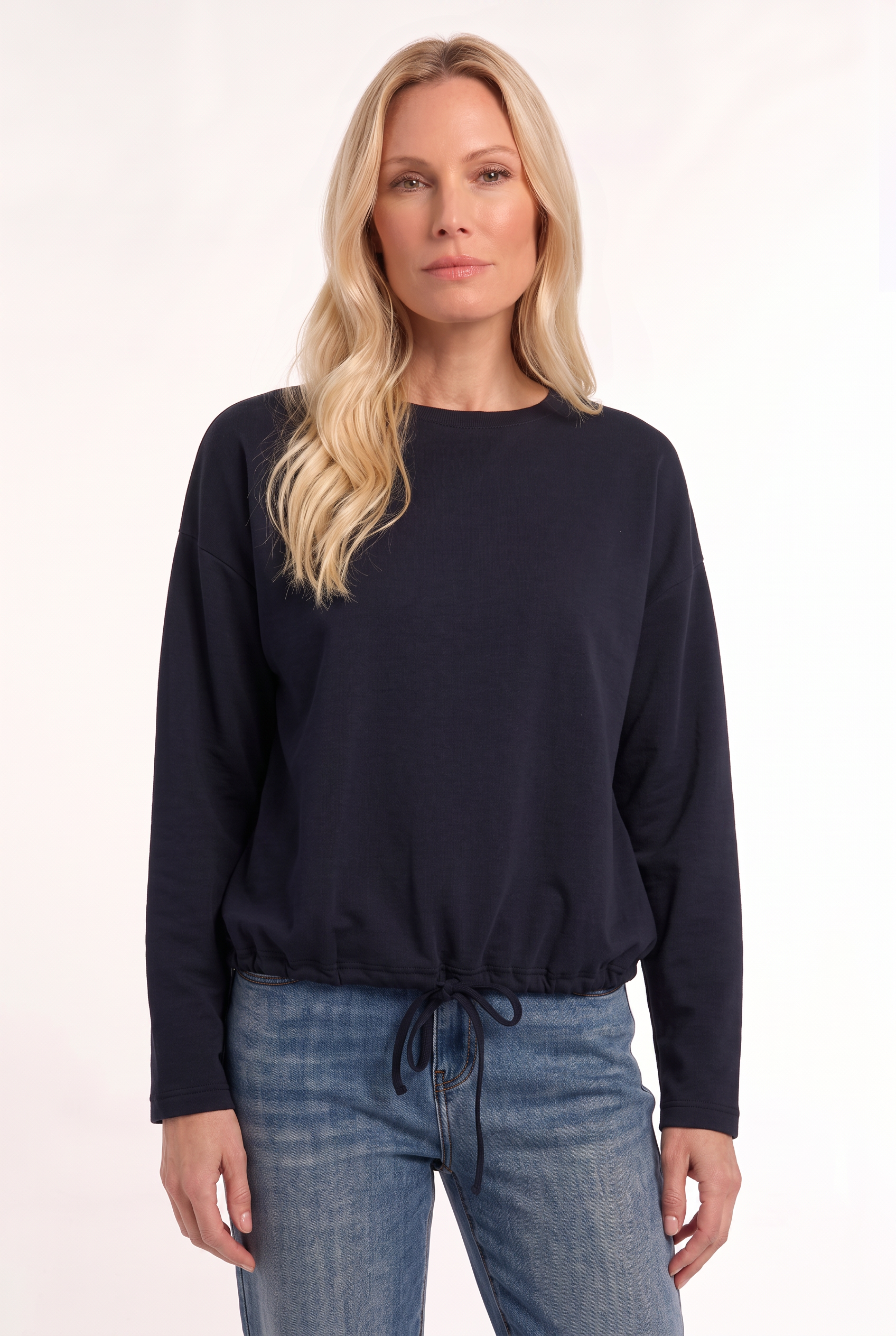 dame draagt donkerblauwe trui met verstelbaar koord aan de onderzijde op een jeans