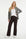 model draagt bruine flared fit travelbroek met daarboven een wit shirt en bruin zwart wit geruite blazer