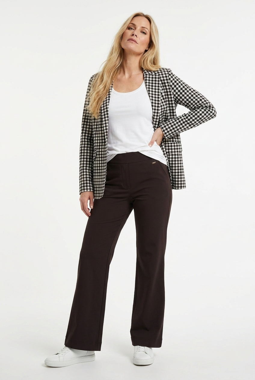 model draagt bruine flared fit travelbroek met daarboven een wit shirt en bruin zwart wit geruite blazer
